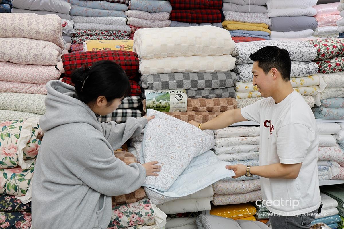 塔洞商會的白色與灰色被子在展示台上的特寫，展示精緻的質地與設計，適合各季節使用的家居用品選擇。