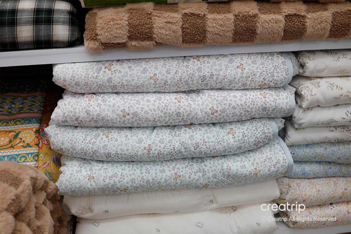 白色與灰色的舒適被子，展現產品標籤如'Tencel'與'Polarfil'，説明這些產品的材質和環保性質。