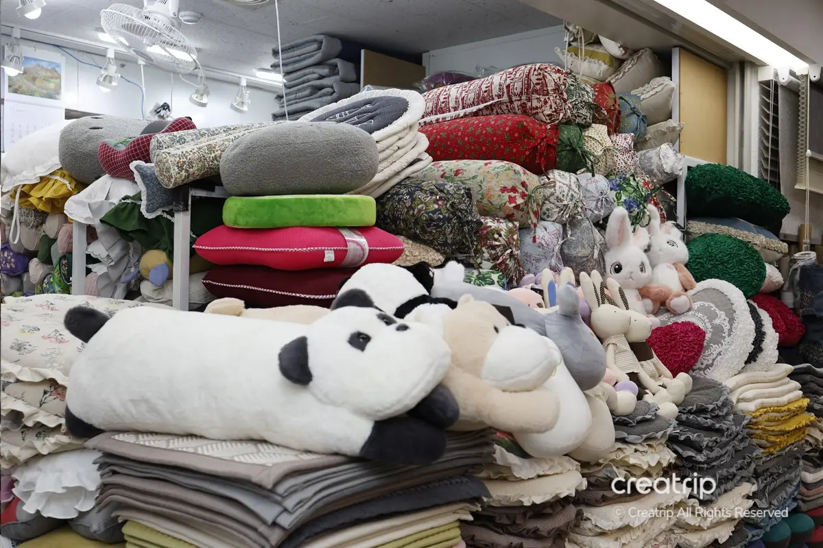 塔洞商會店內，大量的牀墊和枕頭整齊地堆放在貨架上，色彩豐富，包括花紋和卡通圖案等多個選擇。