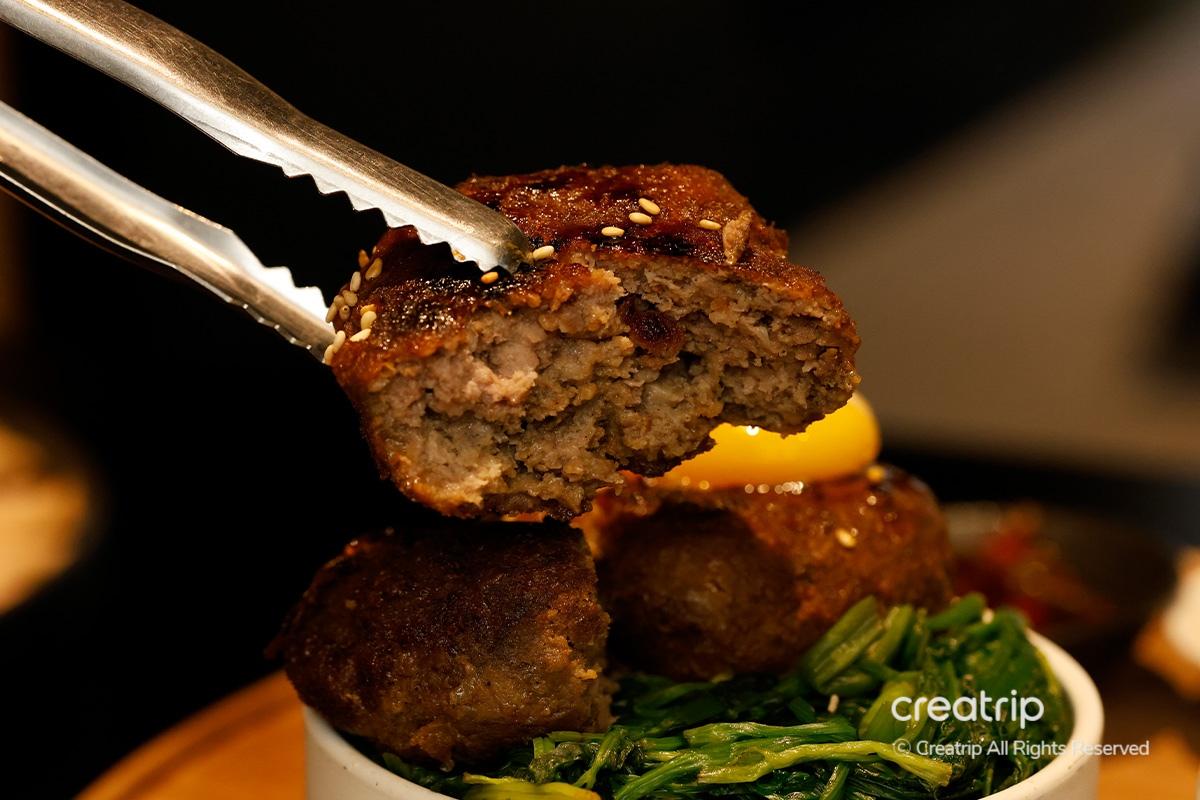 Tteokgalbi servido sobre arroz sazonado en JINJAK KAKII.