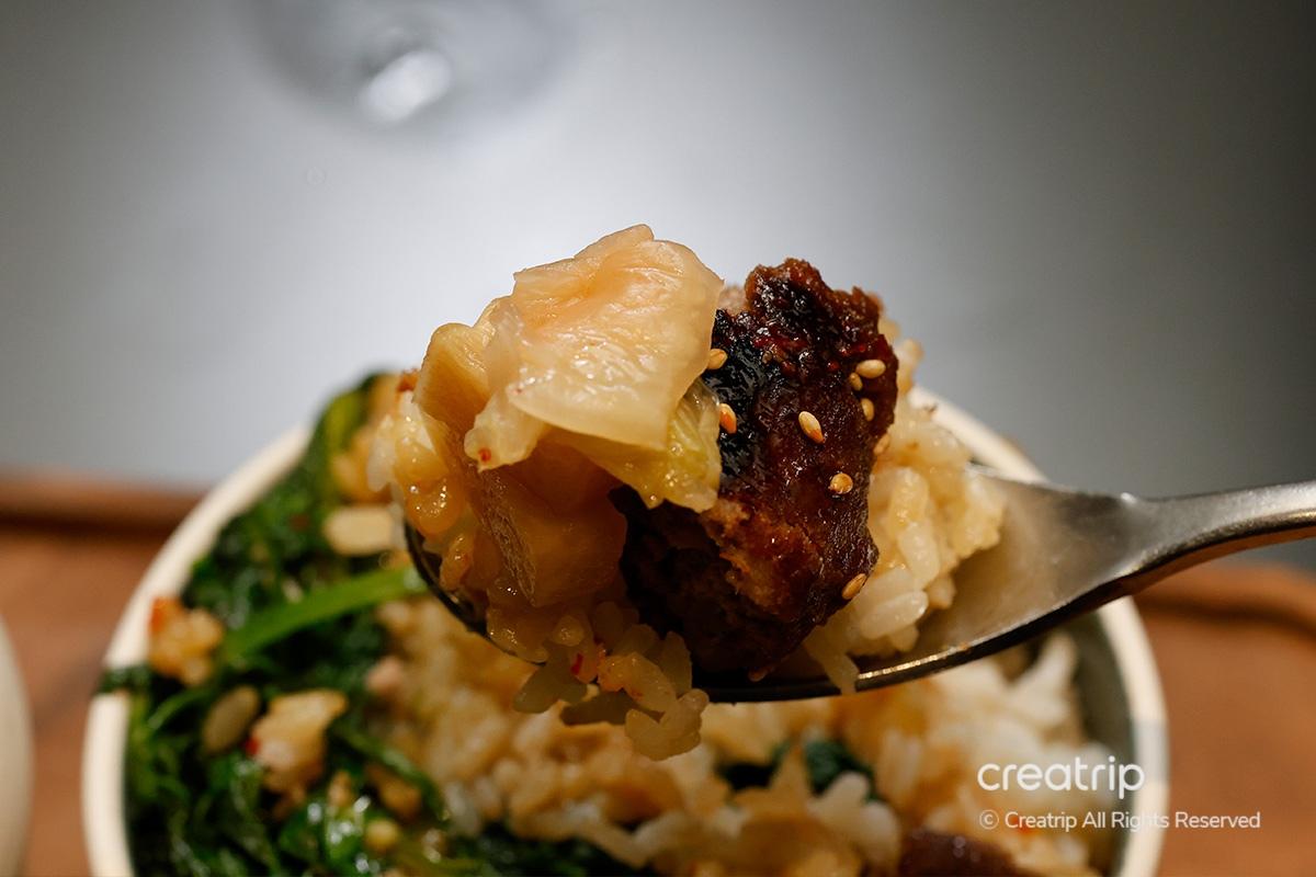 Tteokgalbi y arroz con guarniciones en una cuchara en JINJAK KAKII.