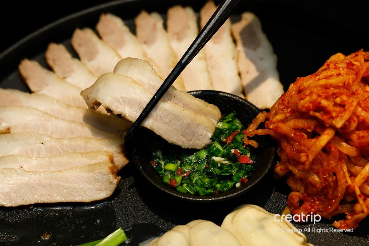 Cerdo hervido de JINJAK KAKII con una guarnición de hierbas frescas.