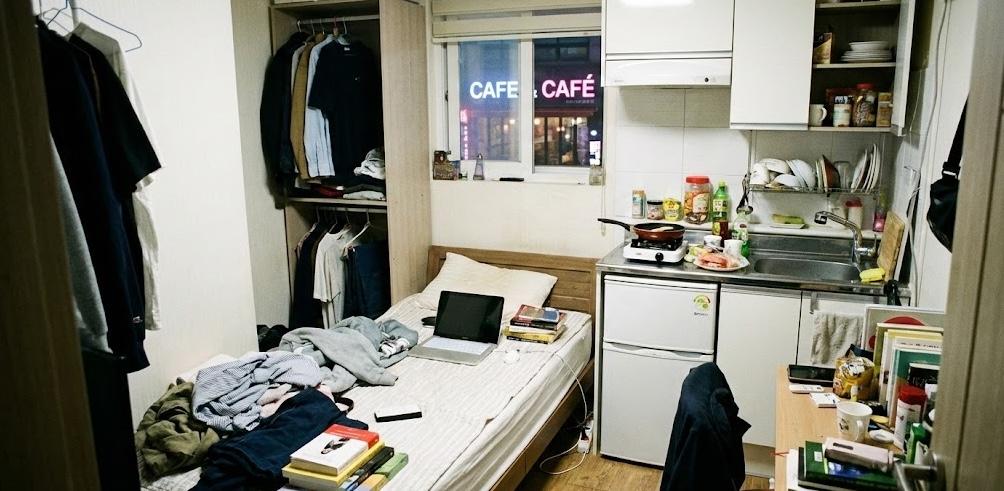 Appartamento monolocale coreano piccolo che mostra uno spazio multifunzionale con un letto, angolo cottura e scrivania, evidenziando la vita compatta a Seoul.