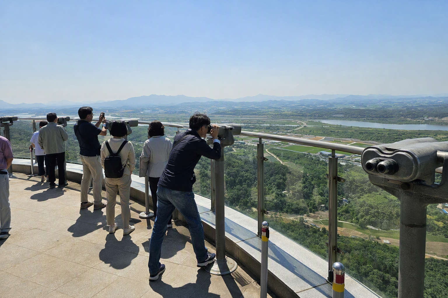 Bright photorealistic view from Dora Observatory, binocular stands facing distant North Korean landscape, clear visibility, vibrant daylight, no Korean text