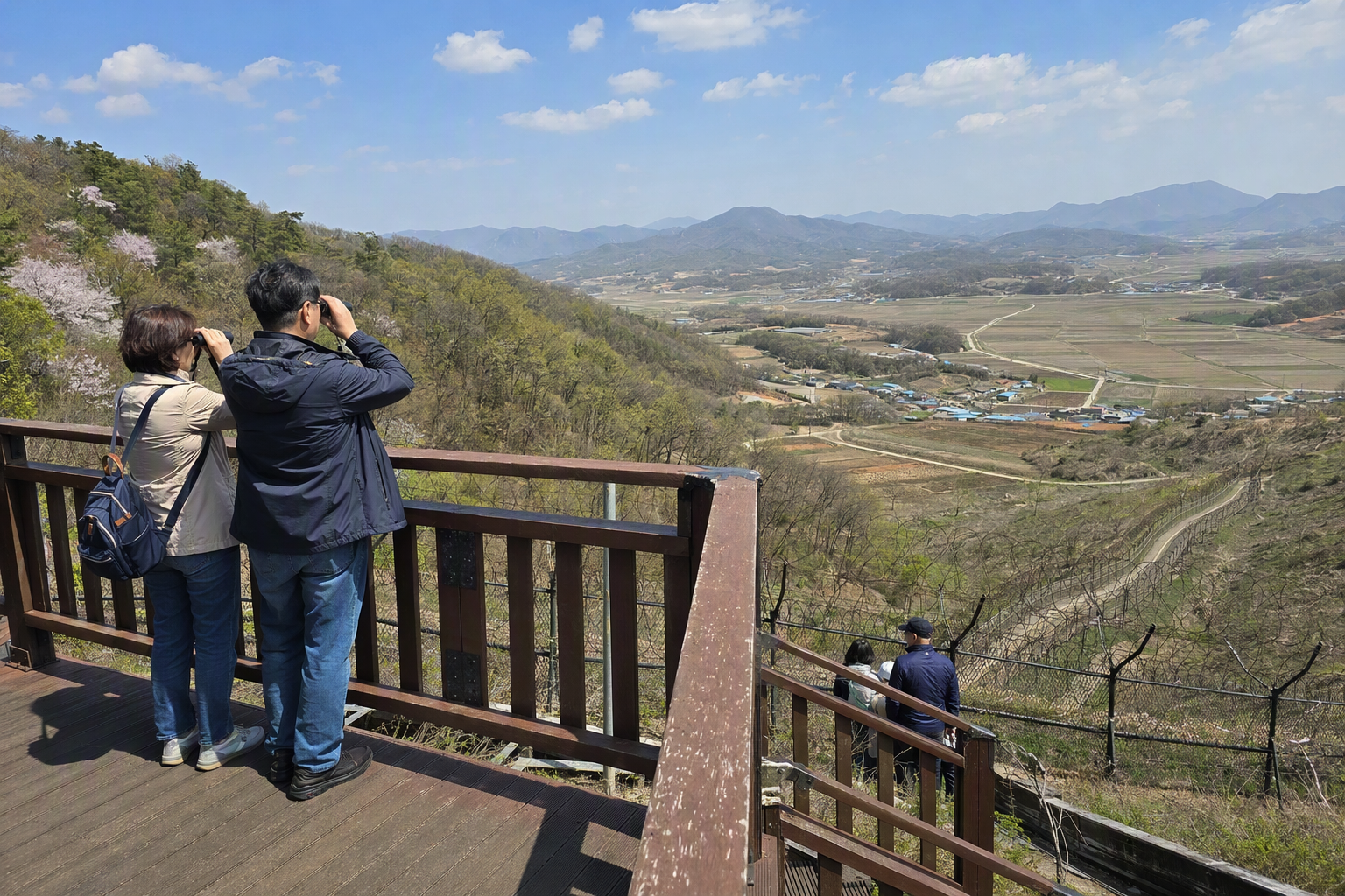 Bright photorealistic border landscape seen from a Korean observatory, fenced hills, distant villages, clear spring sky, vibrant colors, no Korean text