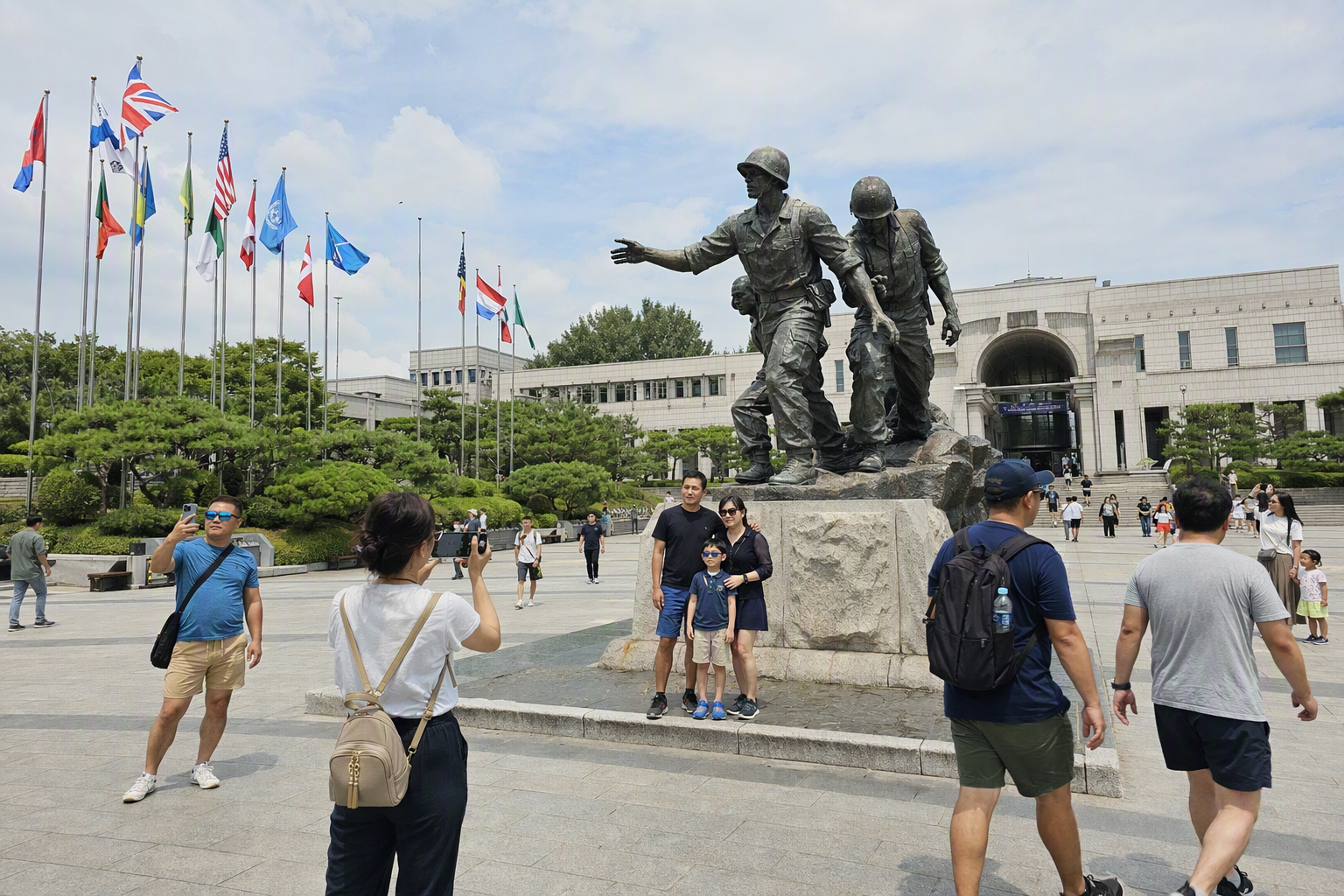 Bright photorealistic view of the memorial plaza and Statue of Brothers, dramatic stone architecture, summer light, visitors taking photos, no Korean text