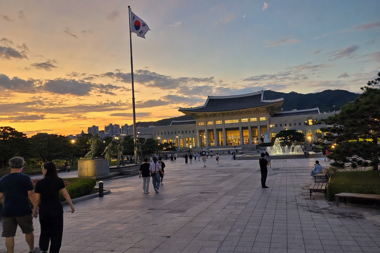 Bright photorealistic sunset view of the War Memorial of Korea plaza, warm light on stone architecture, peaceful evening sky, no Korean text