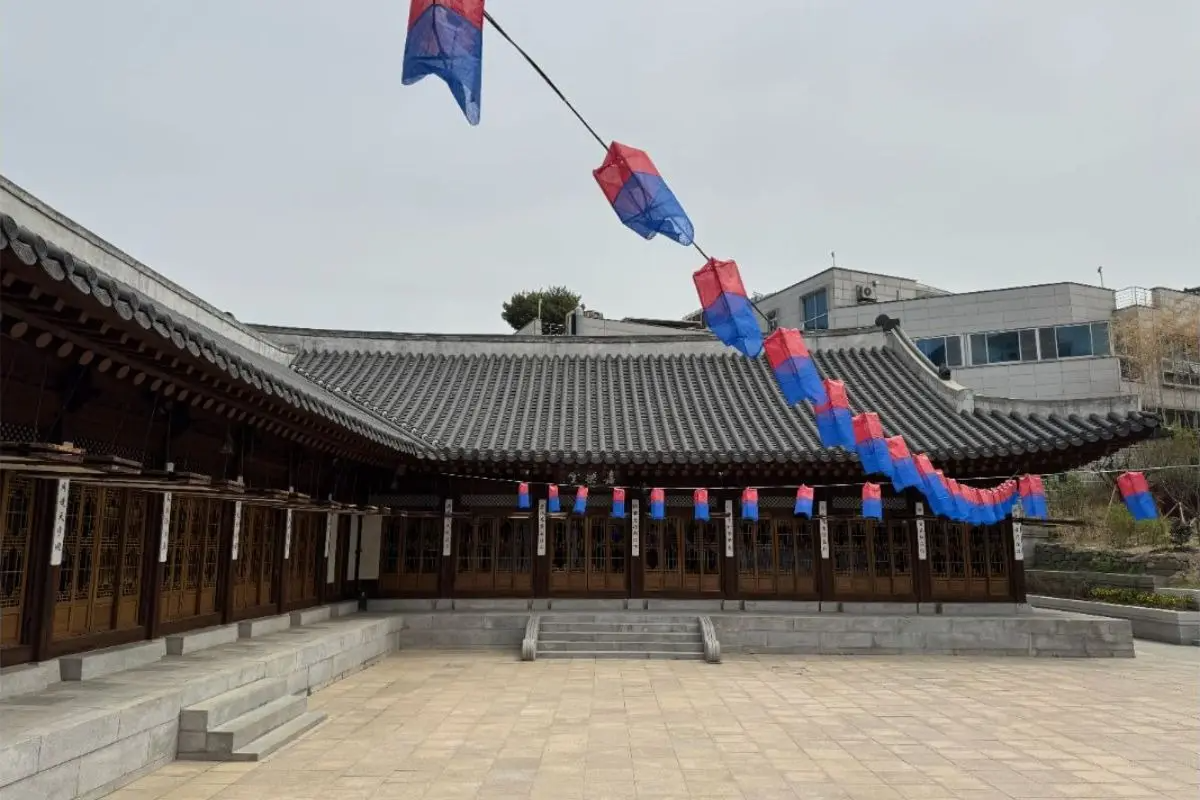 Traditional Hanok courtyard at Korea House Kohojae with wooden doors, tiled roof, and red-blue lanterns strung above the plaza