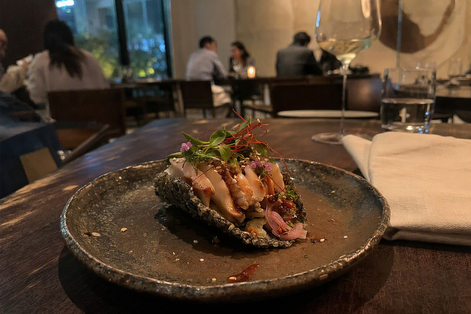 明亮鮮豔、寫實風格的近拍照片，一道現代韓式精緻料理，靈感來自鮑魚塔可，搭配細緻配菜與陶瓷餐盤，在優雅餐廳燈光下呈現