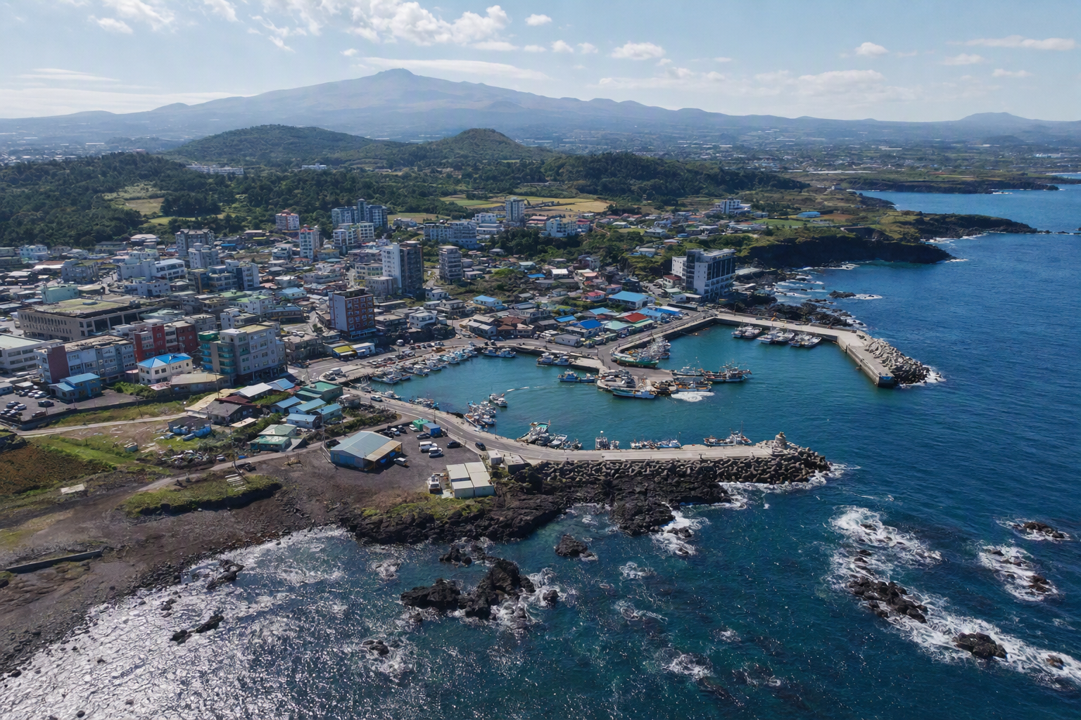bright vibrant photorealistic view of Jeju coastal city and blue ocean from above, volcanic hills in the distance, sunny day, no text