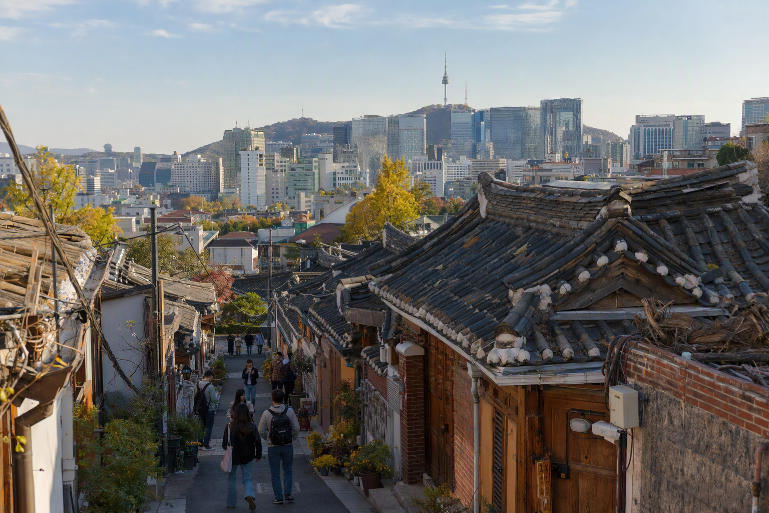 在藍天下、溫暖午後光線中，傳統瓦屋屋頂與現代首爾建築並列的明亮寫實場景，無文字