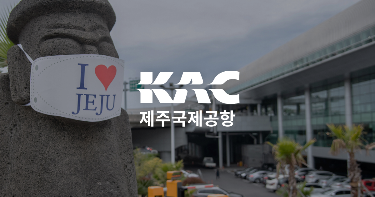 濟州國際機場外觀與停車場，前景石頭守護神戴著寫有“I ♥ JEJU”的口罩，適合旅遊攻略封面使用（機場標誌清晰）。