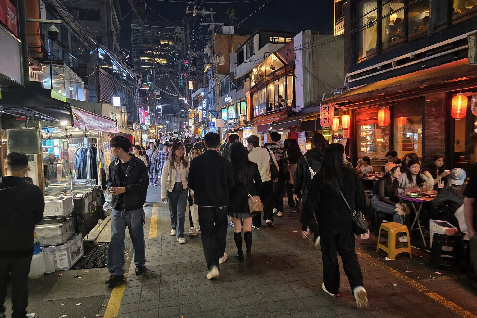 明亮寫實風的弘大夜晚街景，有年輕旅人、咖啡廳與音樂氛圍，彩色燈光，畫面中無可辨識招牌或文字