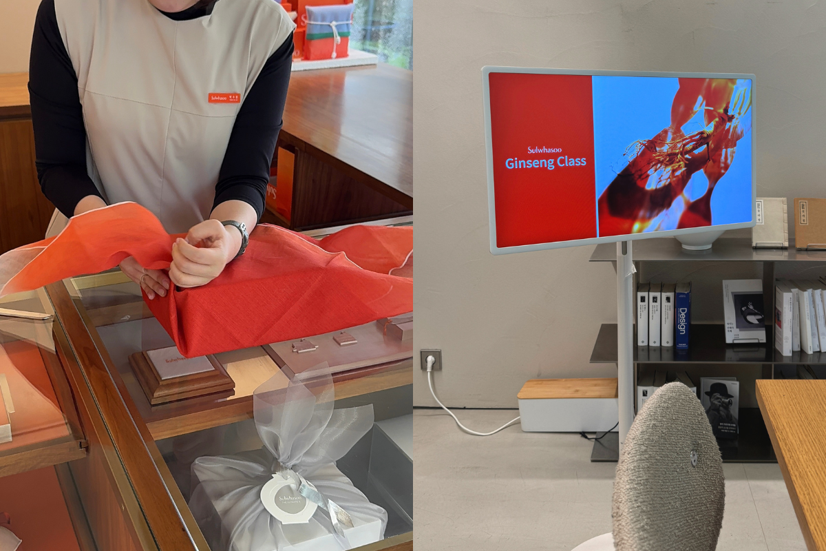 Staff member at Sulwhasoo Bukchon House wrapping a red gift box in traditional bojagi cloth, with branded gift boxes on display, chairs, and a screen showing “Ginseng Class.”