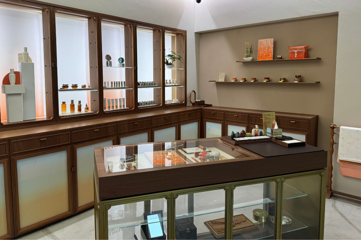 Nội thất Sulwhasoo Bukchon House với tủ trưng bày bằng gỗ, tủ kính, chai dưỡng da, bộ quà tặng, ánh sáng cam dịu và chi tiết tường lấy cảm hứng từ thủ công truyền thống.