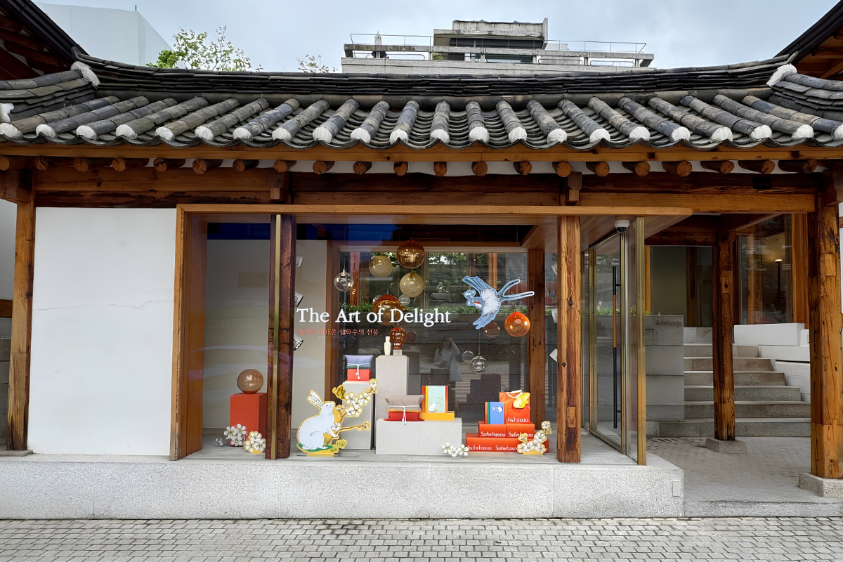 Sulwhasoo Bukchon House entrance display with traditional roof tiles, wooden beams, orange gift boxes, and bird and rabbit illustrations.
