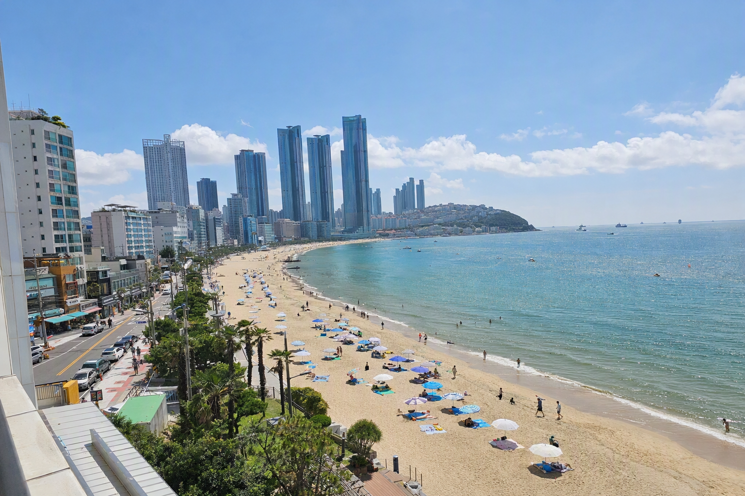 Bright vibrant photorealistic view of Busan coastline with Haeundae Beach, blue ocean, high-rise skyline, sunny weather, no Korean text