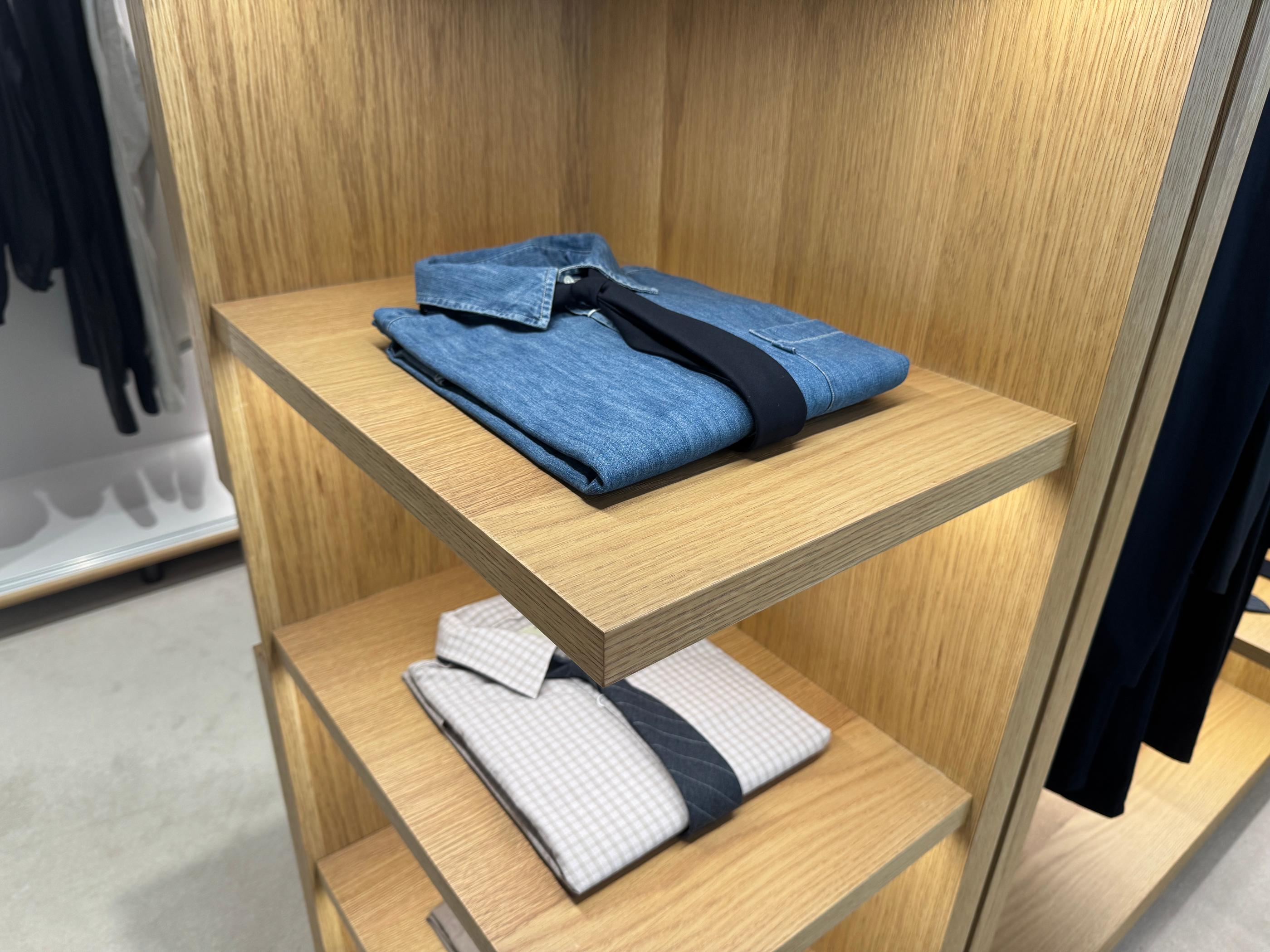 Pottery menswear display featuring a crisp white dress shirt paired with a dark silk tie on a wooden hanger