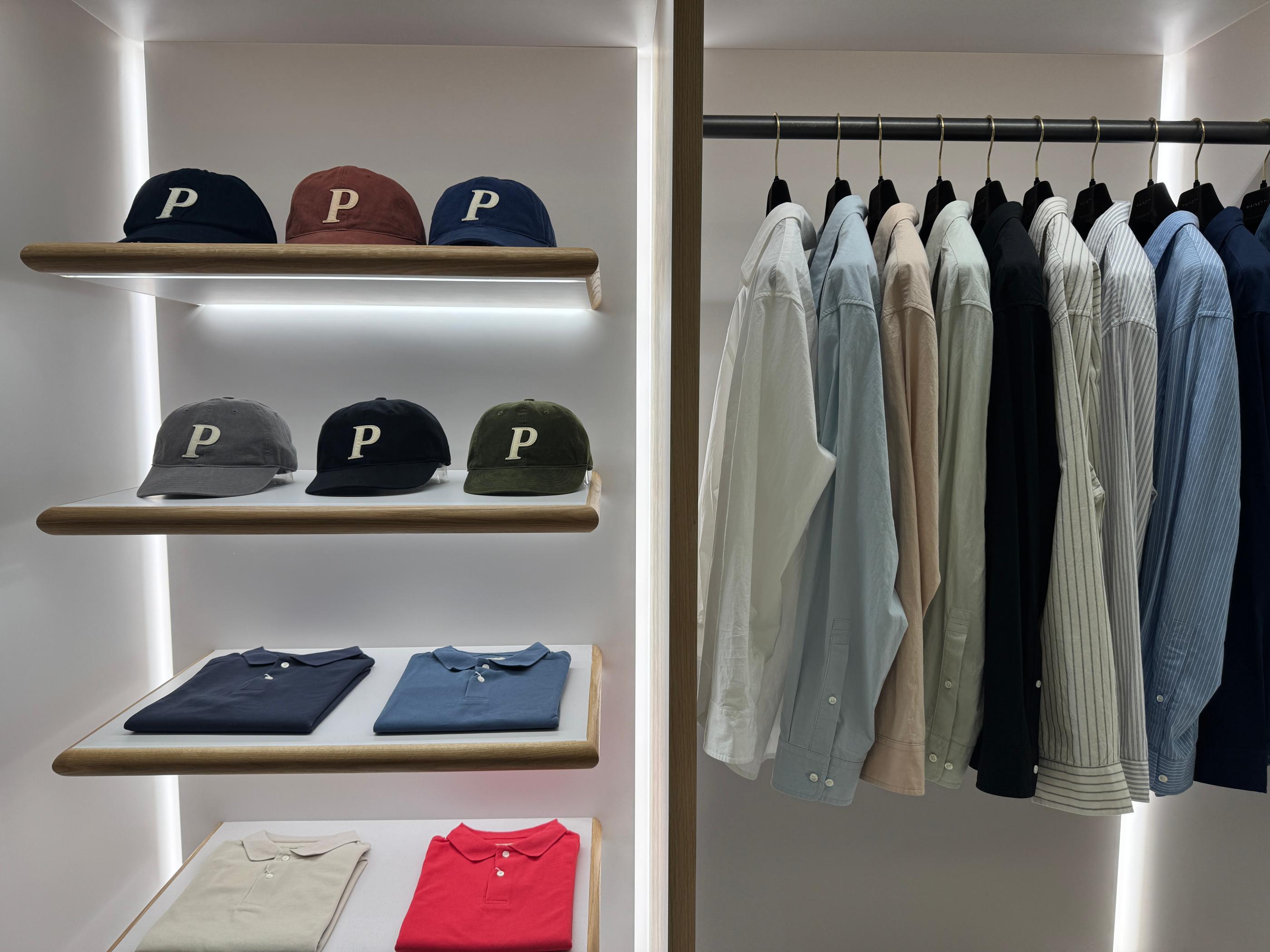 Pottery Seongsu store shelf display with signature P-logo caps and folded polo shirts in cream and beige tones on an illuminated lightbox