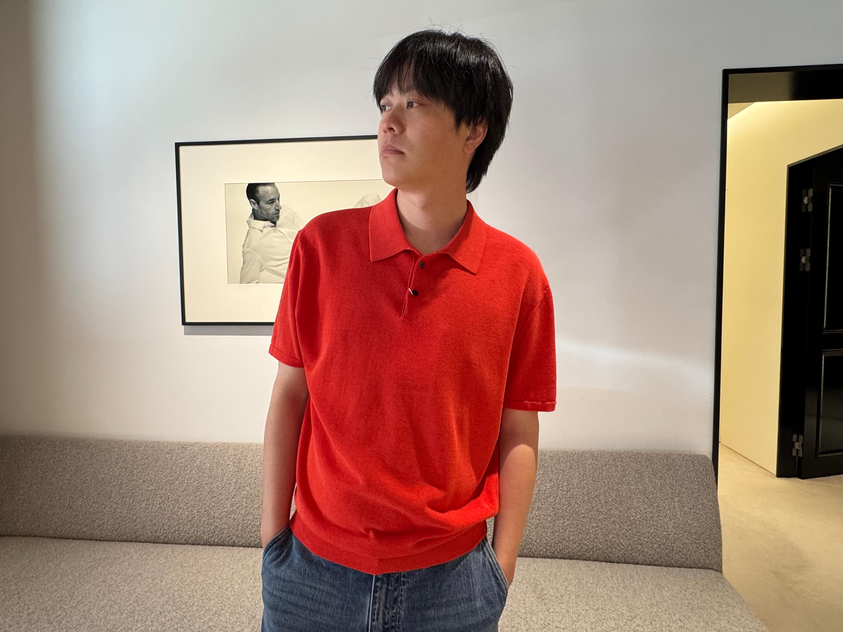 Model in Pottery Seongsu store wearing a brick-red knit polo with relaxed jeans, minimalist interior and framed photo in background