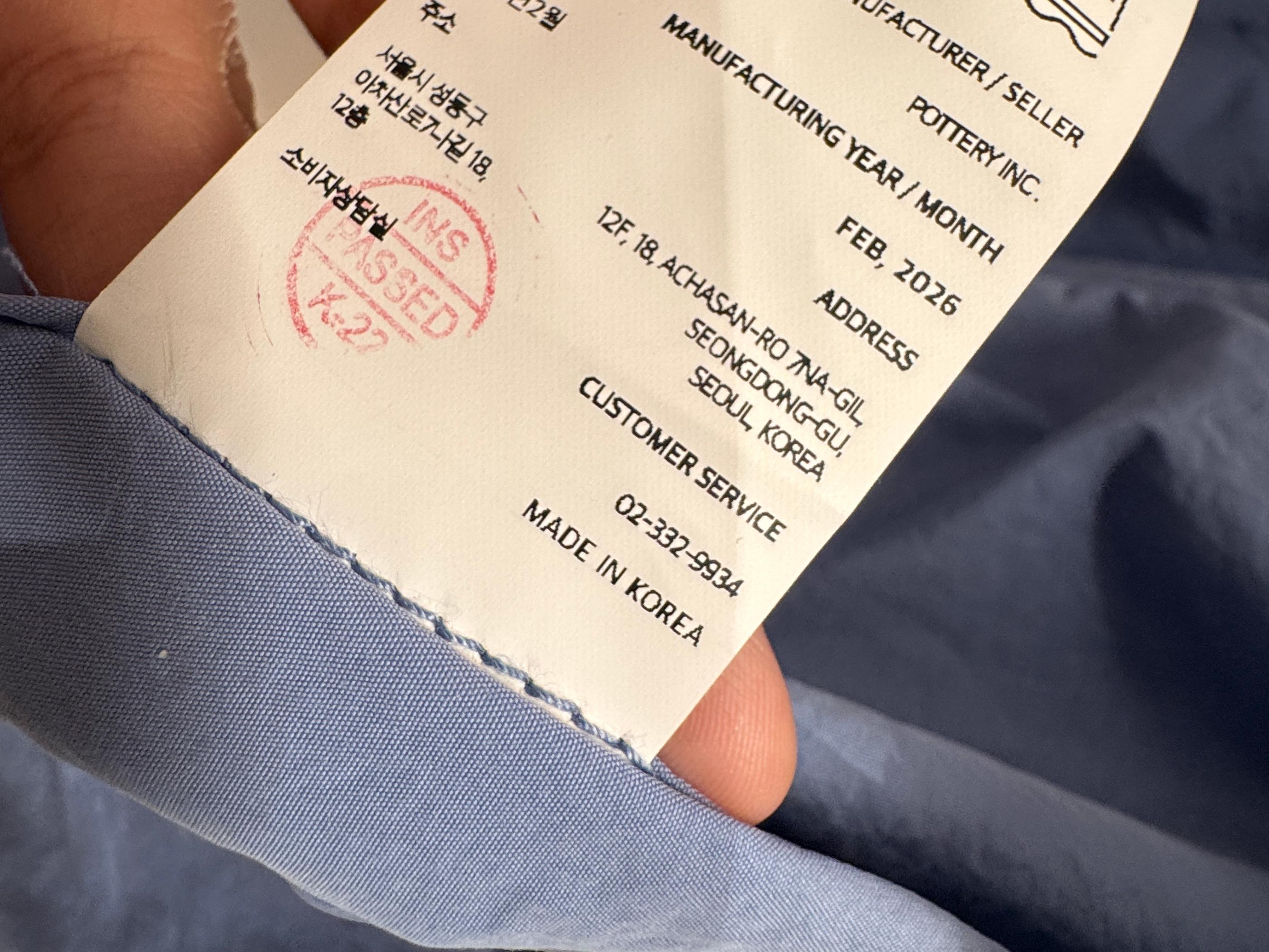 Close-up of Pottery care label showing Made in Korea mark and fabric composition details on a linen garment