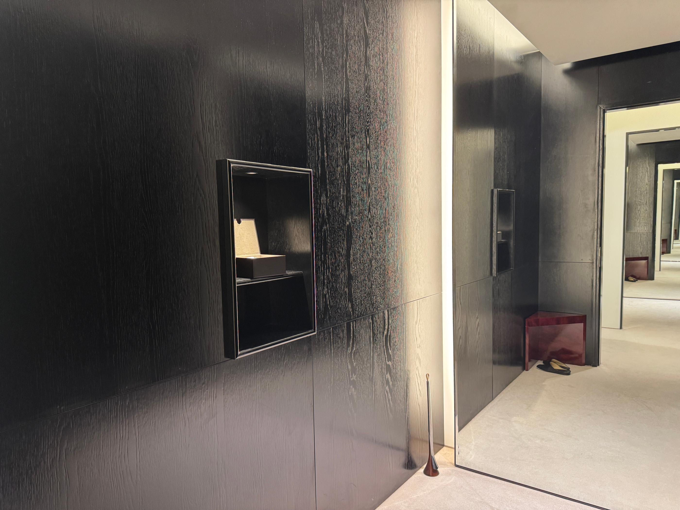 Minimal Pottery Seongsu fitting room with dark wood panels, recessed display shelf, full-length mirror and seating area with slippers