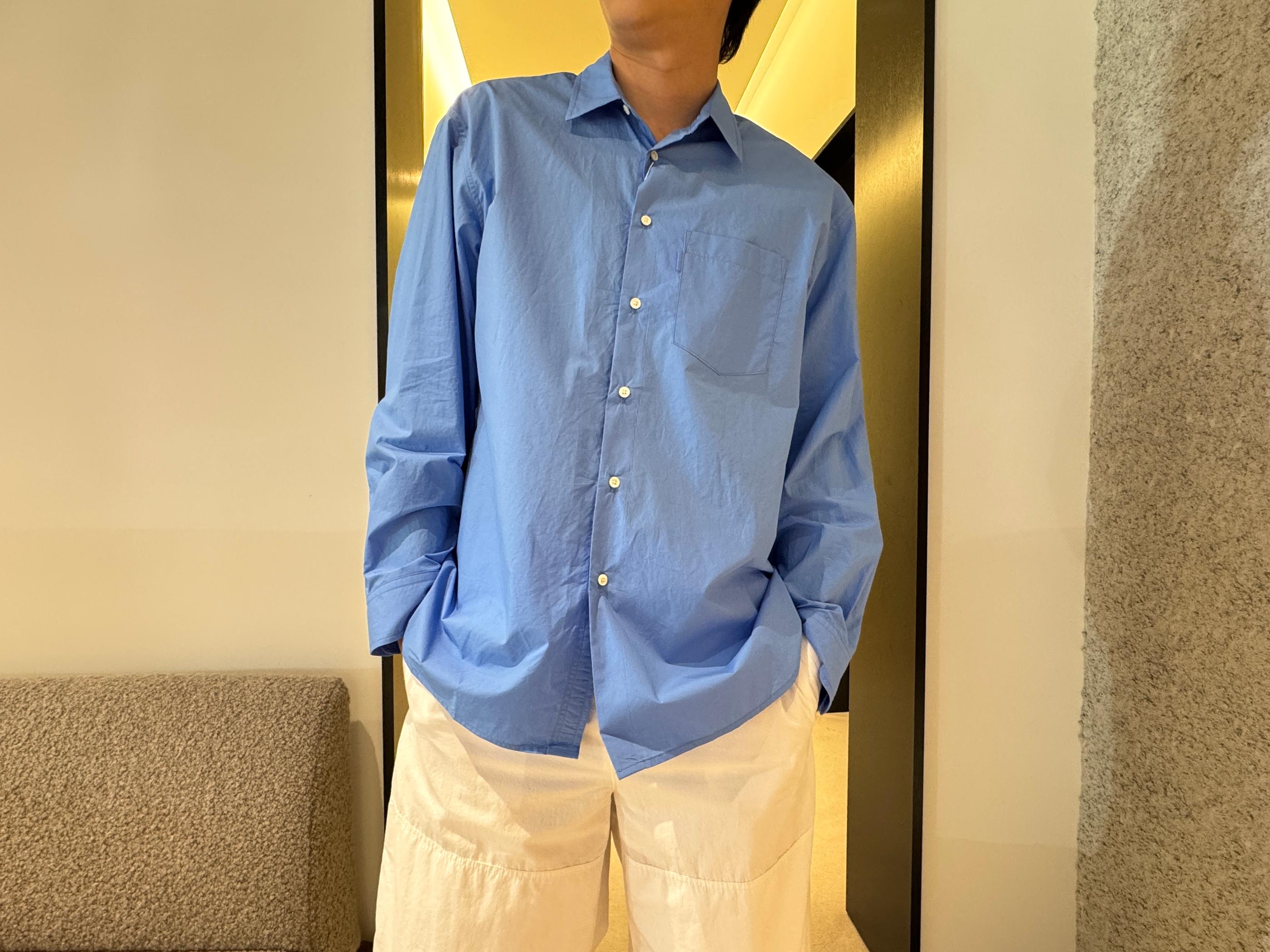 Model wearing a relaxed sky-blue button shirt and off-white wide-leg pants in Pottery Seongsu store, showcasing minimalist Korean menswear.