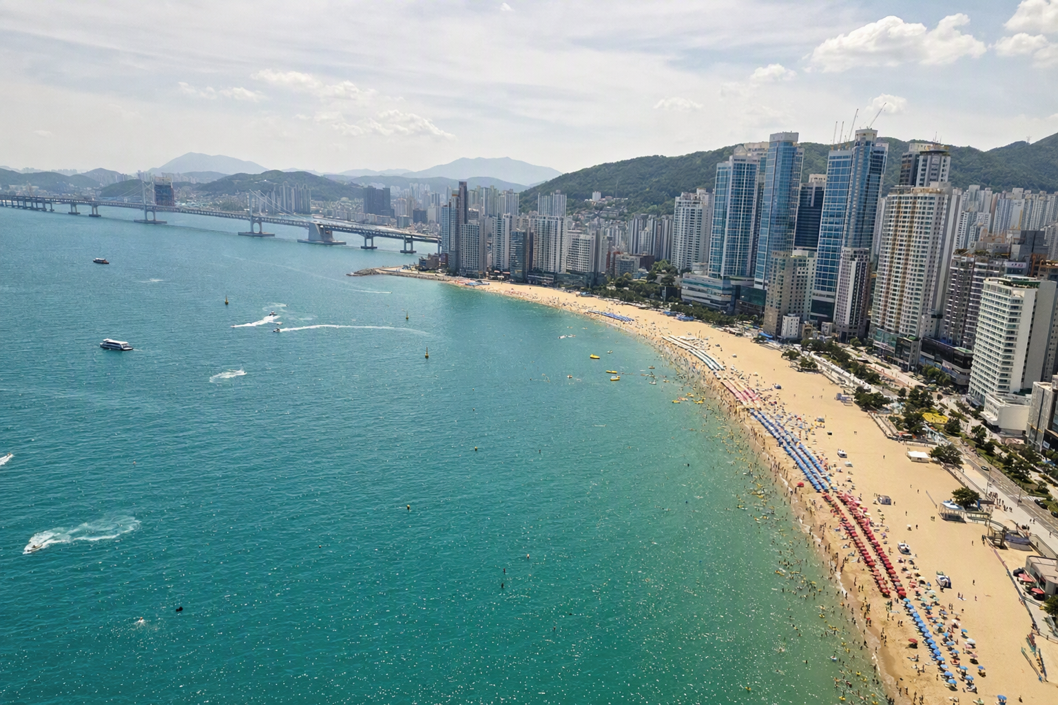 明亮、充滿活力、寫實風格的釜山海岸線全景，可見海雲臺海灘、高樓群、藍色海面與晴朗天空，畫面中無可見文字