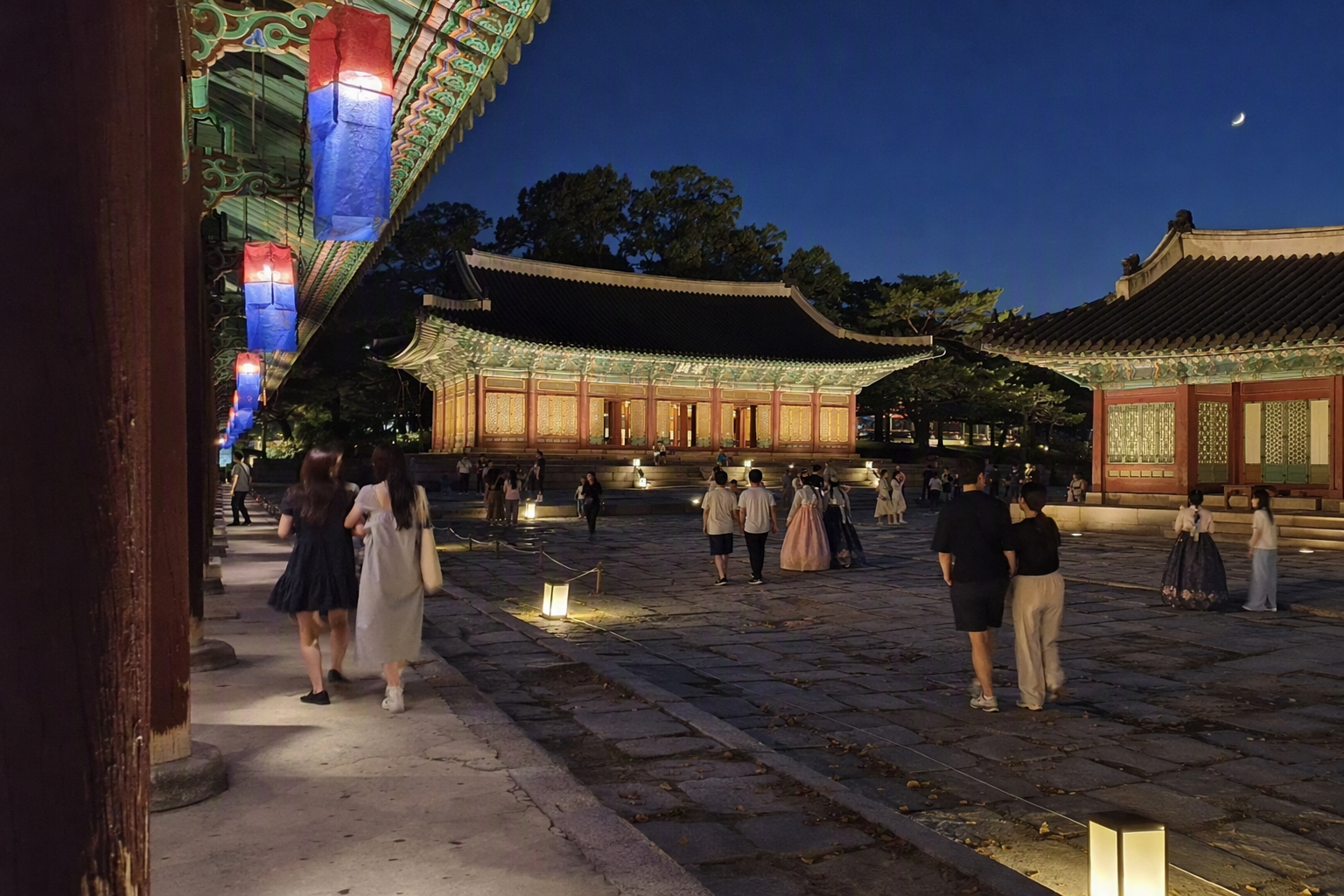 以溫暖燈籠照亮的韓國王宮庭院寫實夜景，傳統建築，遊客安靜走動，色彩鮮明，無