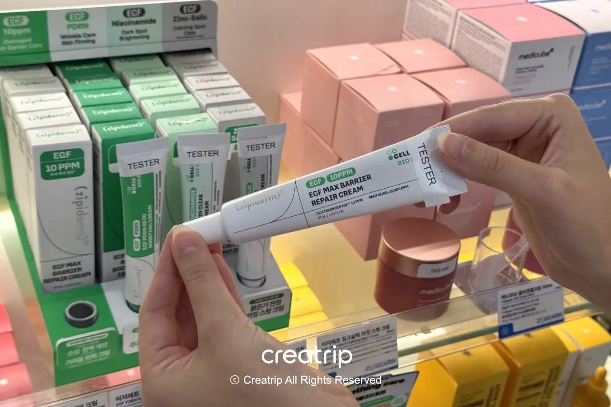 在藥局貨架前用雙手拿著zipiderm EGF Max Barrier Repair Cream軟管的樣子