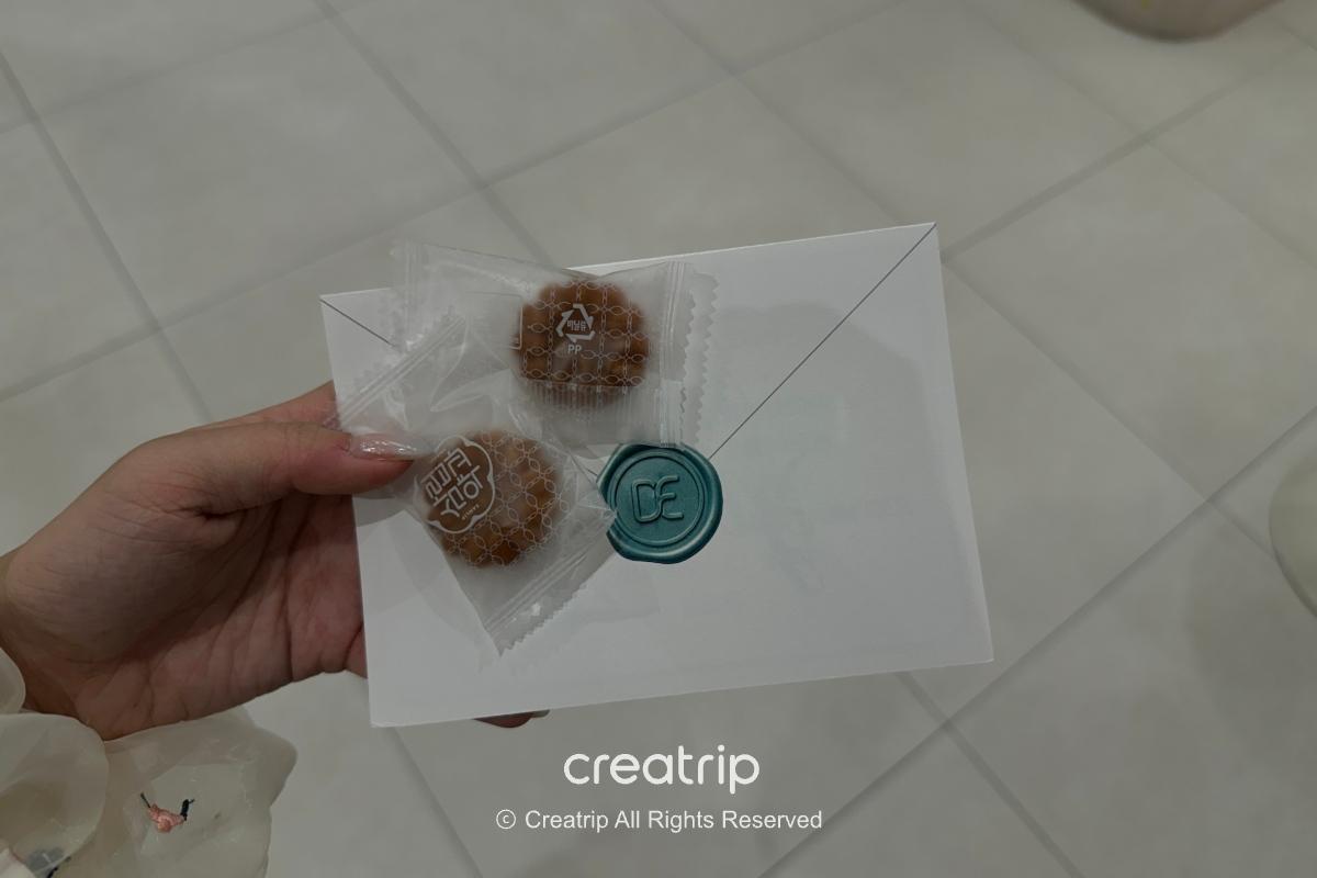 Hand holding a wrapped yakgwa cookie and thank-you card
