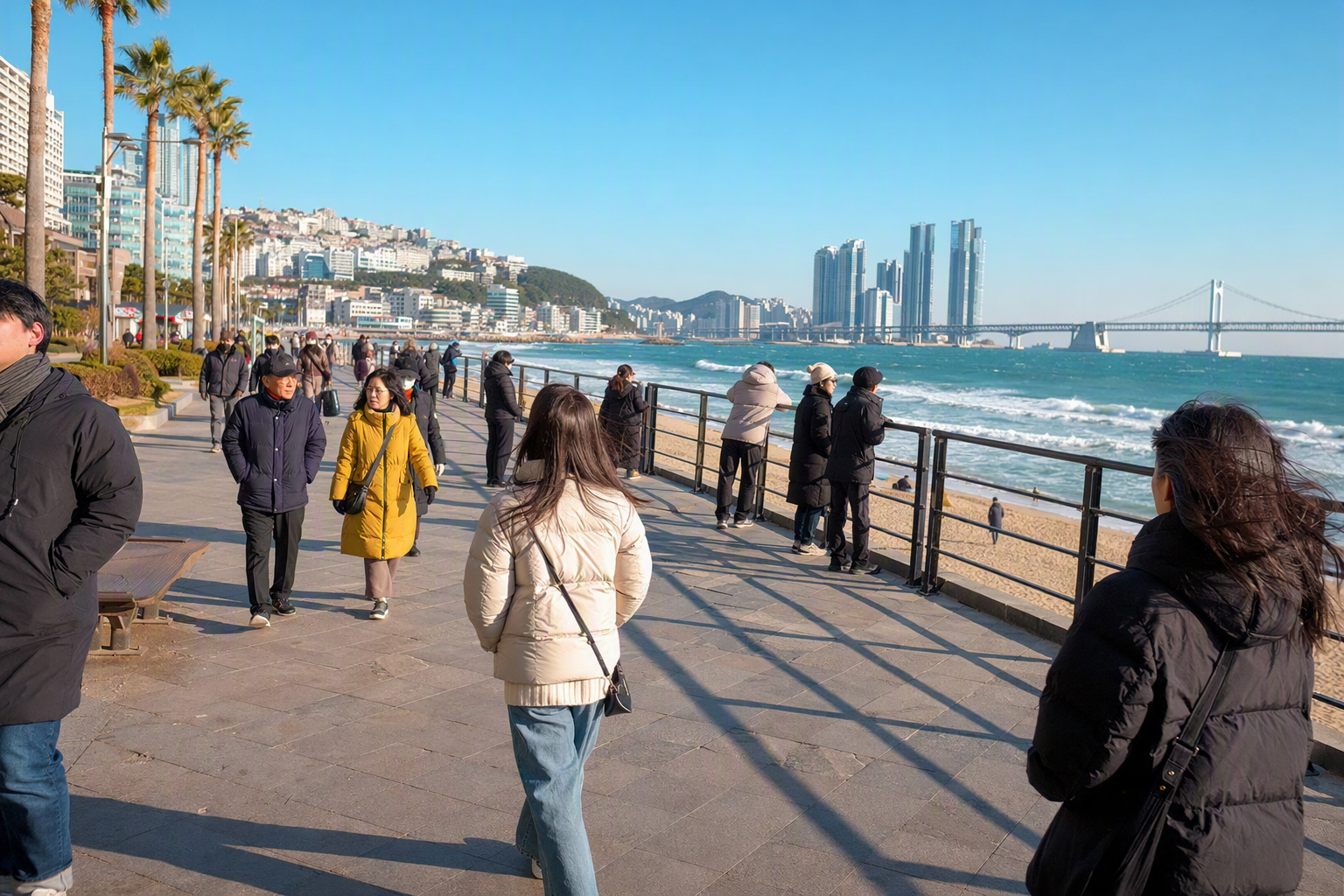 Bright vibrant photorealistic Busan seaside promenade in December, mild sunlight, ocean waves, travelers with light winter coats, no visible text
