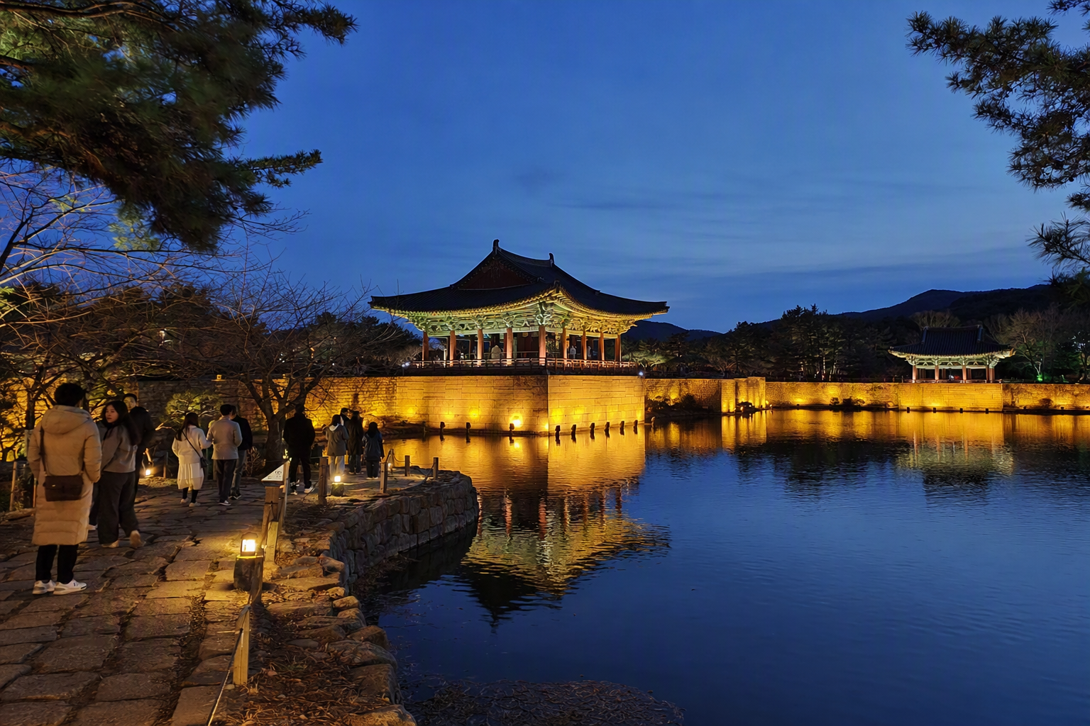 色彩鮮明寫實風慶州東宮與月池夜景，燈光照亮嘅樓閣倒映喺平靜水面，優雅旅遊雜誌風格
