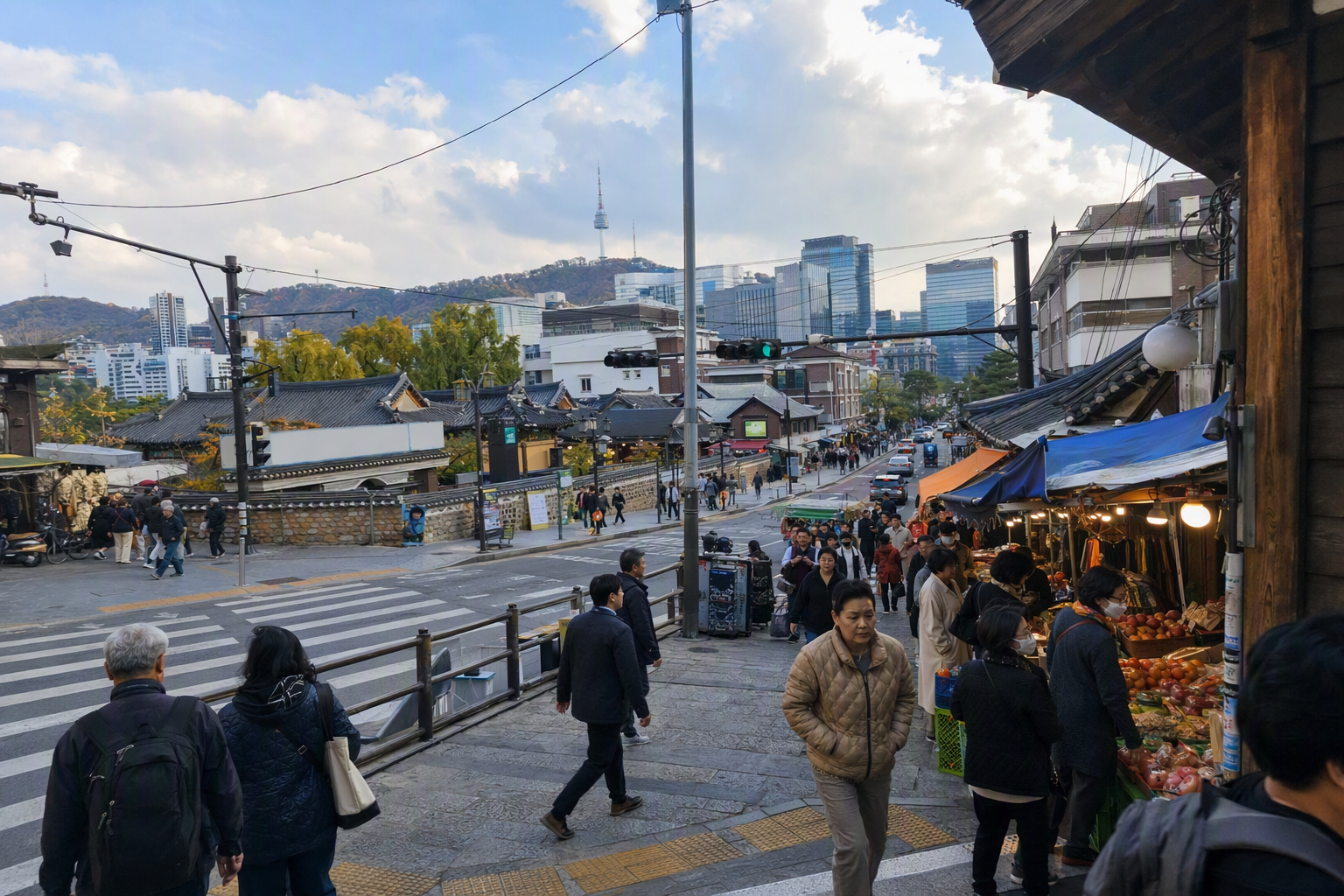 明亮、充滿活力的寫實強對比場景，畫面呈現首爾，前景是老市場巷弄，遠處可見宮殿屋脊、現代摩天大樓、擁擠的人行穿越道，以及更遠方的山景
