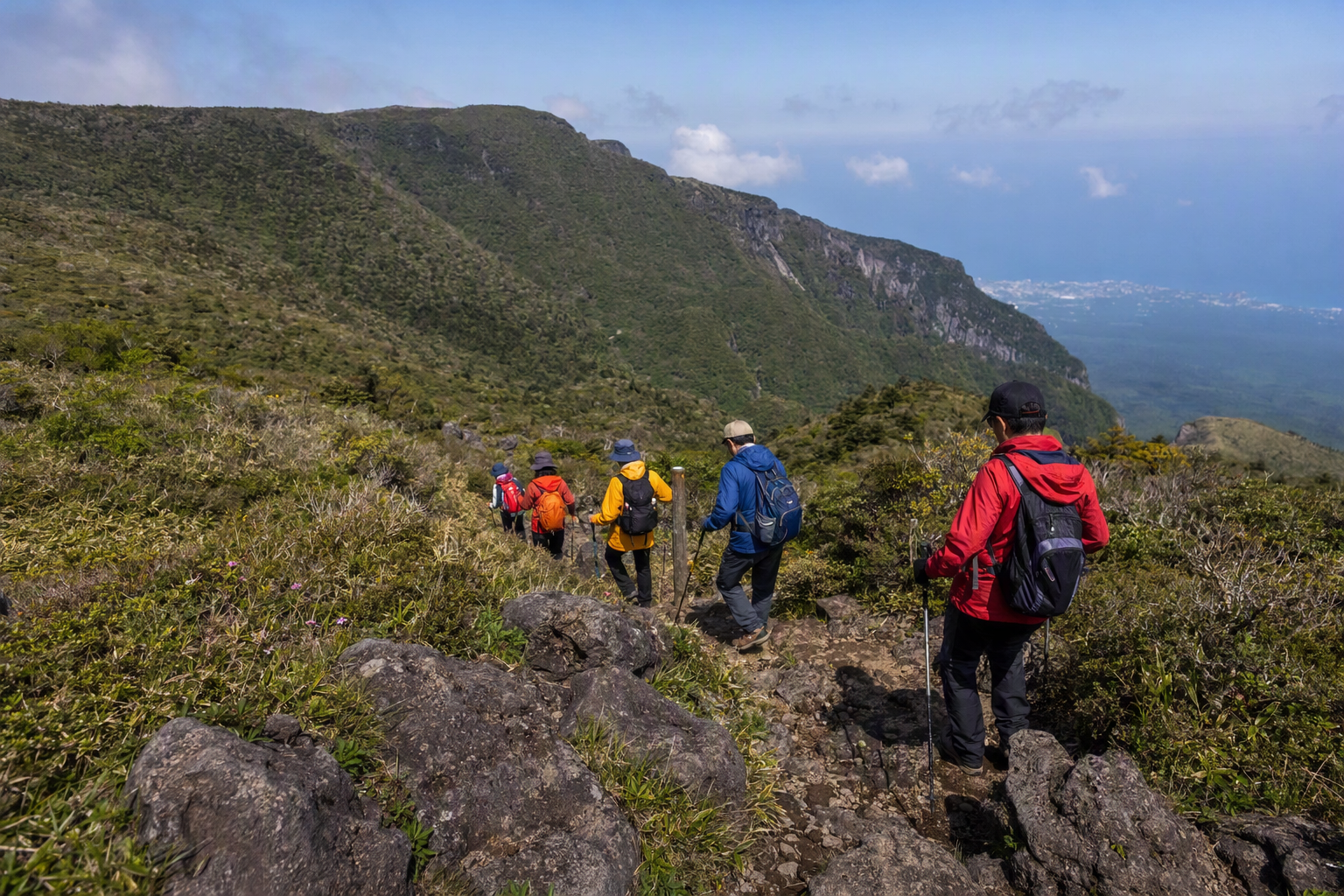 濟州漢拏山步道，火山岩與綠色山坡，穿著亮色外套的健行者，天空晴朗，明亮鮮豔的寫實風格照片，畫面無文字