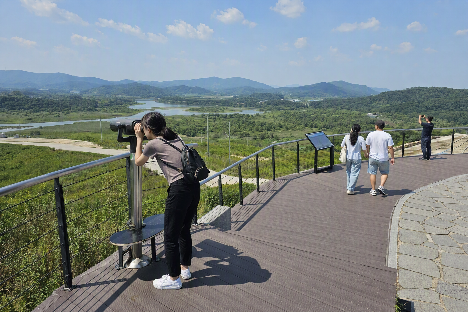 Bright, vibrant, photorealistic view of a peaceful DMZ observation landscape with wide sky, green fields, distant hills, and a quiet viewing platform, no Korean
