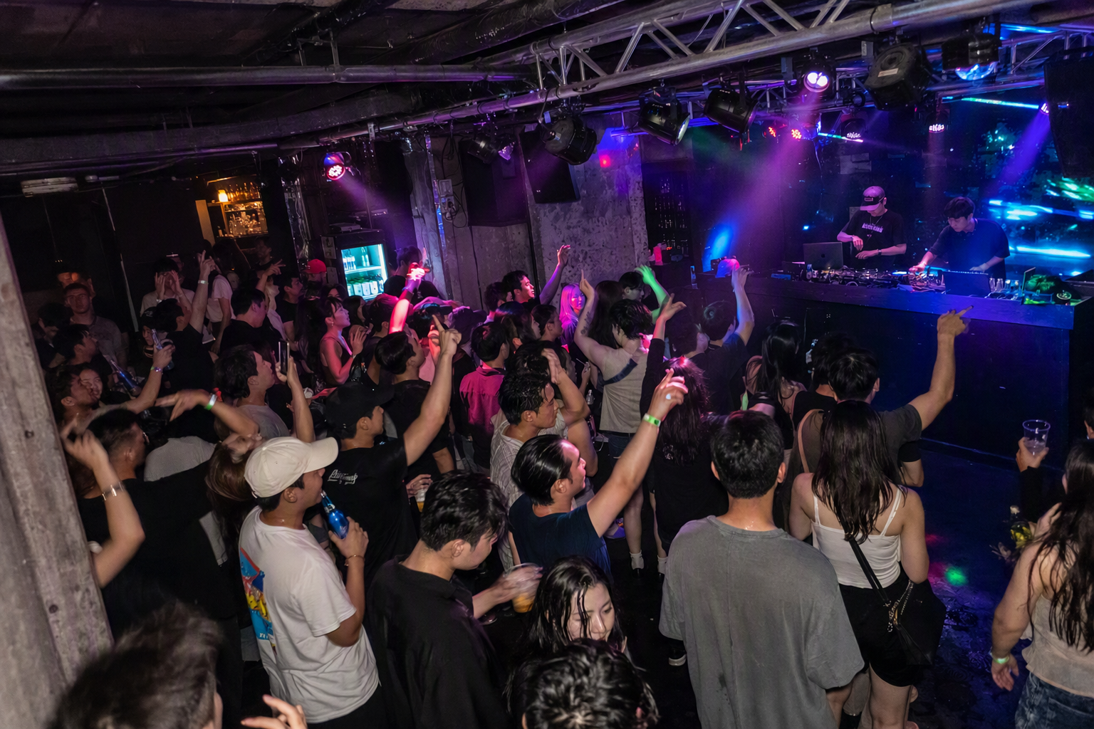 Bright vibrant photorealistic Itaewon underground club interior, colorful lights over a packed dance floor, diverse international crowd, DJ booth, intimate base
