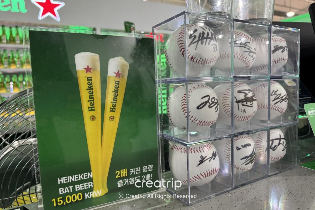 海尼根酒吧吧台上的宣传牌与签名棒球收藏，展示两支大容量球棒生啤广告与透明方格内排列的签名棒球，呼应机场酒吧打卡氛围。