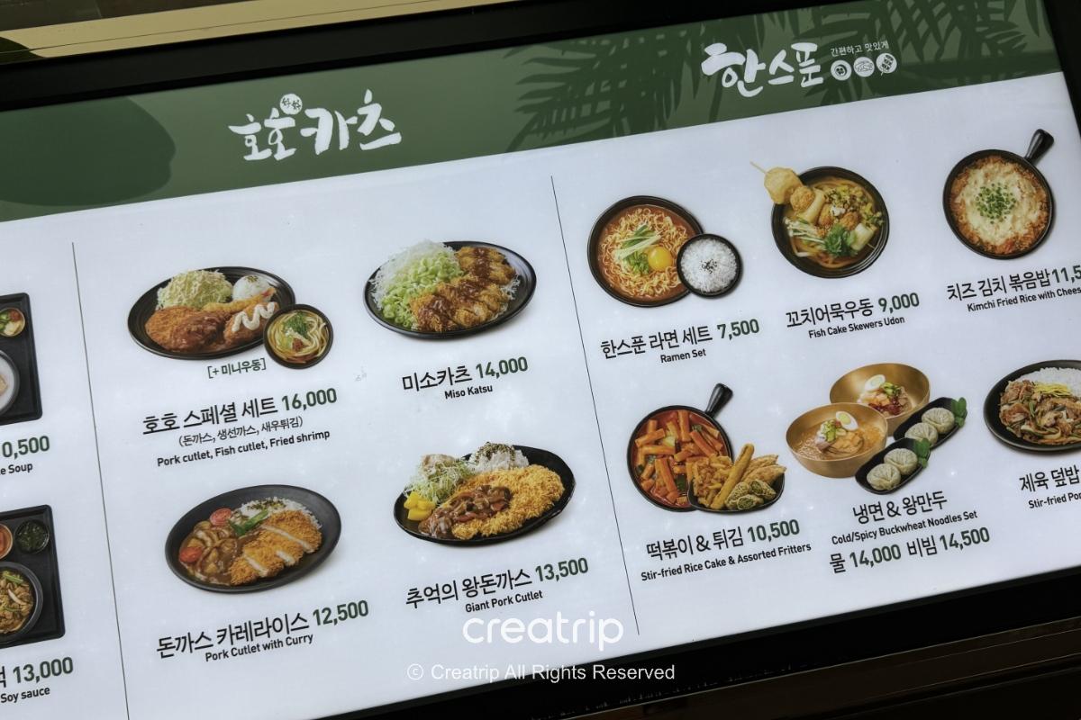 釜山金海机场HAN SPOON菜单看板，展示炸猪排、猪排咖哩、拉面、炒年糕与炸物等韩式机场餐点照片与价格，适合准备登机或抵达后快速觅食的参考画面。