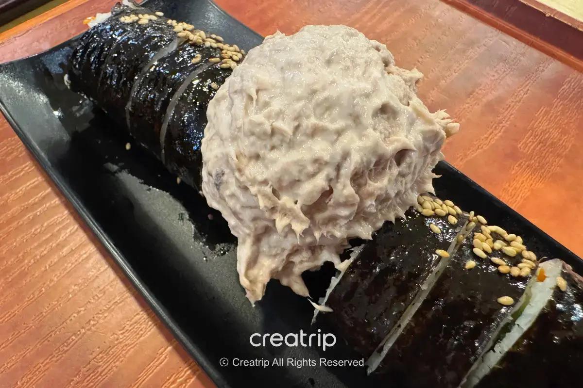金海機場PLE美食街的韓式飯捲切片擺盤，淋上芝麻並配上一大球鮪魚美乃滋，適合抵達或出發前快速外帶或內用的機場小吃。