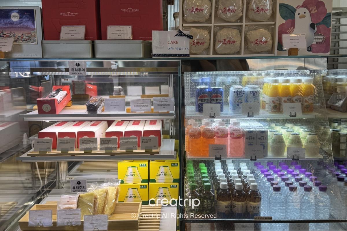 机场面包店展示柜内的三明治、烘焙礼盒与各式瓶装饮料，标示与包装清楚，适合抵达或出发旅客快速购买外带点心。