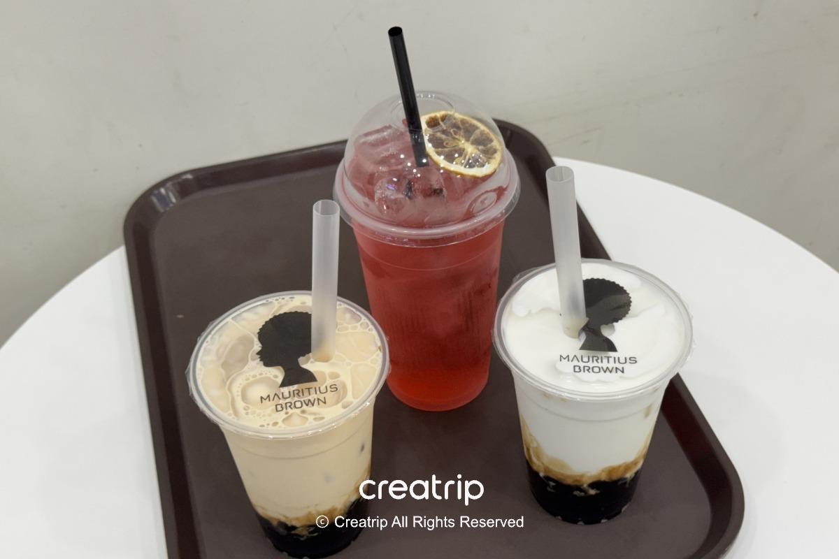 釜山金海機場Mauritius Brown的三杯飲品：兩杯珍珠奶茶與一杯紅色水果茶，放在托盤上適合抵達或外帶候機享用