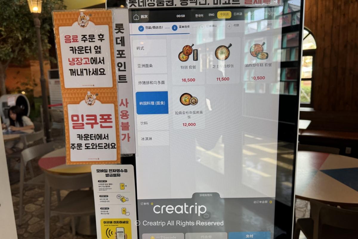 釜山樂天世界Joyful Food Plaza自助點餐機螢幕顯示中文菜單與價格，旁邊有韓文提示牌與餐廳內座位與窗外光線，呈現現場點餐與用餐環境。