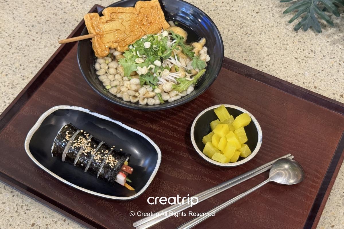 釜山樂天世界Joyful Food Plaza套餐：魚板烏龍麵搭配紫菜飯捲與醃蘿蔔，擺在木托盤上自助餐具，適合家人或遊園時快速用餐的韓式組合