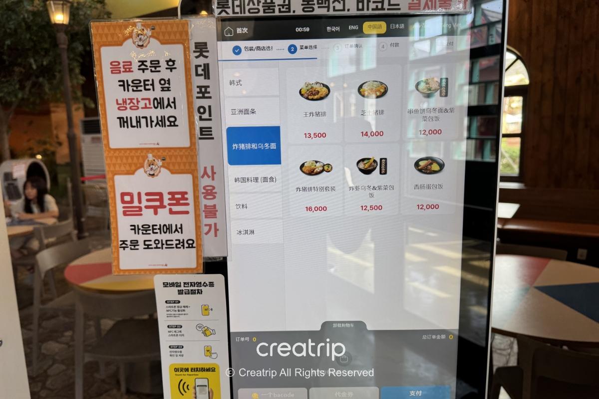 樂天世界美食廣場自助點餐機畫面，中文菜單與餐點圖示、價位顯示，旁邊貼有取餐與飲料領取說明，背景可見室內座位區，適合家庭用餐