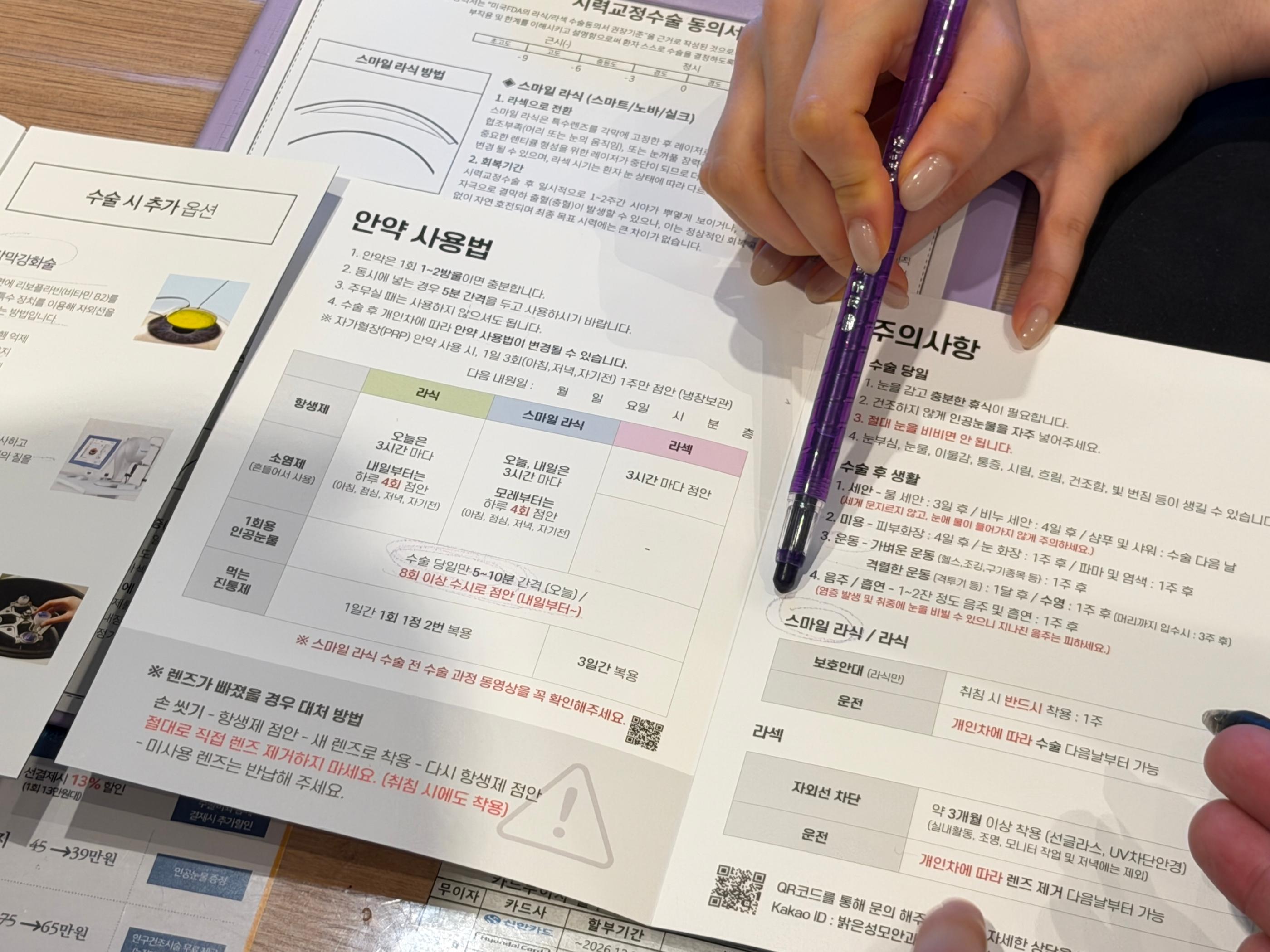 診所桌上攤開的術前說明與用藥說明單，手持紫色筆指向重點，旁邊有醫療宣傳摺頁與患者手部，呈現預約報到與術前講解情境，適合赴韓近視雷射流程介紹。