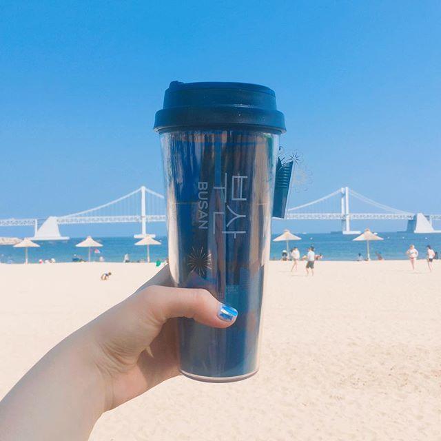 星巴克釜山市烟火图案杯子，在广安里的背景下拍照，请展示其精致设计。