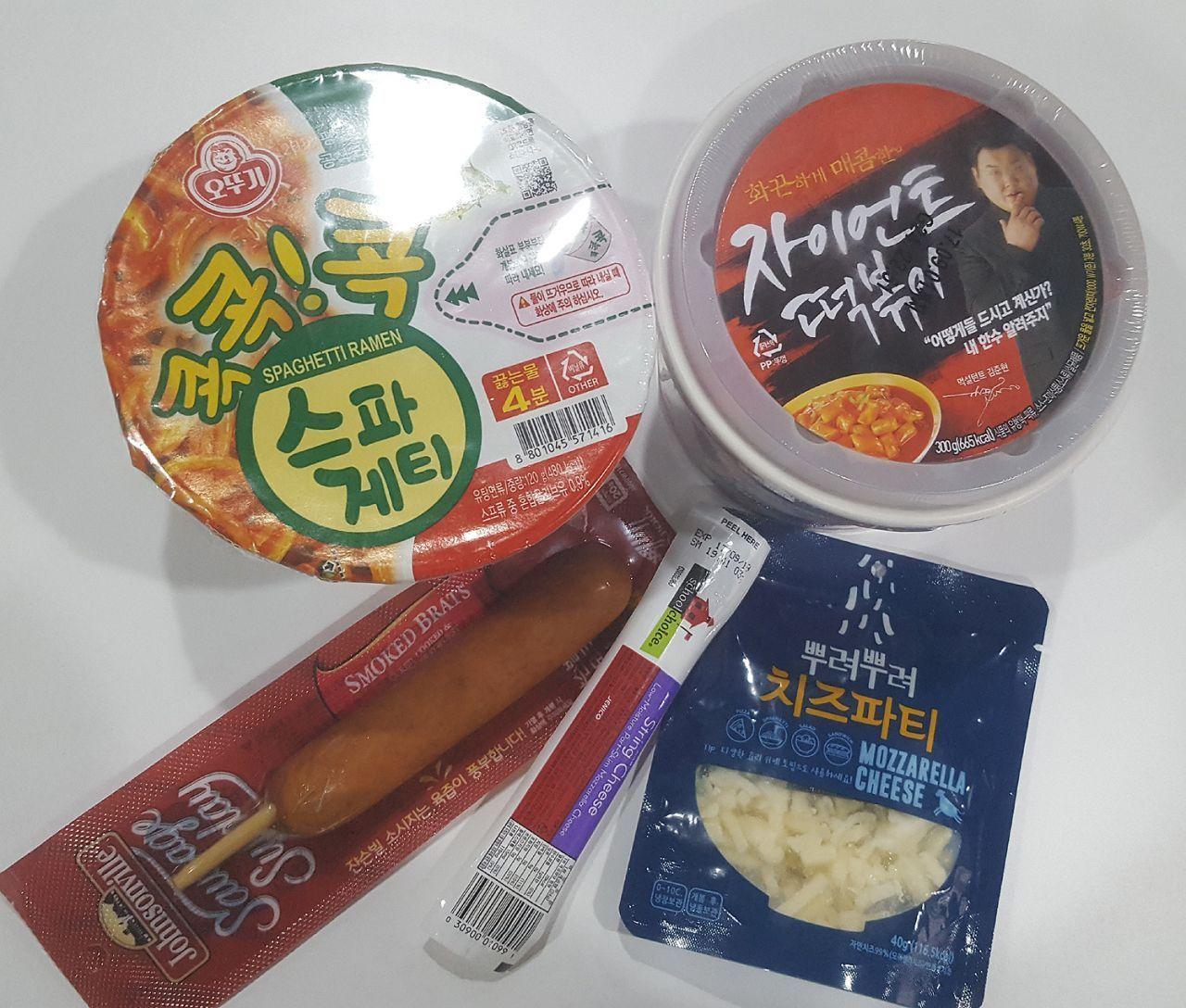 Ingredients for making Mark meal at home, including cup noodles, spicy rice cakes, frankfurter sausage, mozzarella cheese, and cheese sticks, highlighting the simple preparation with convenience store items.