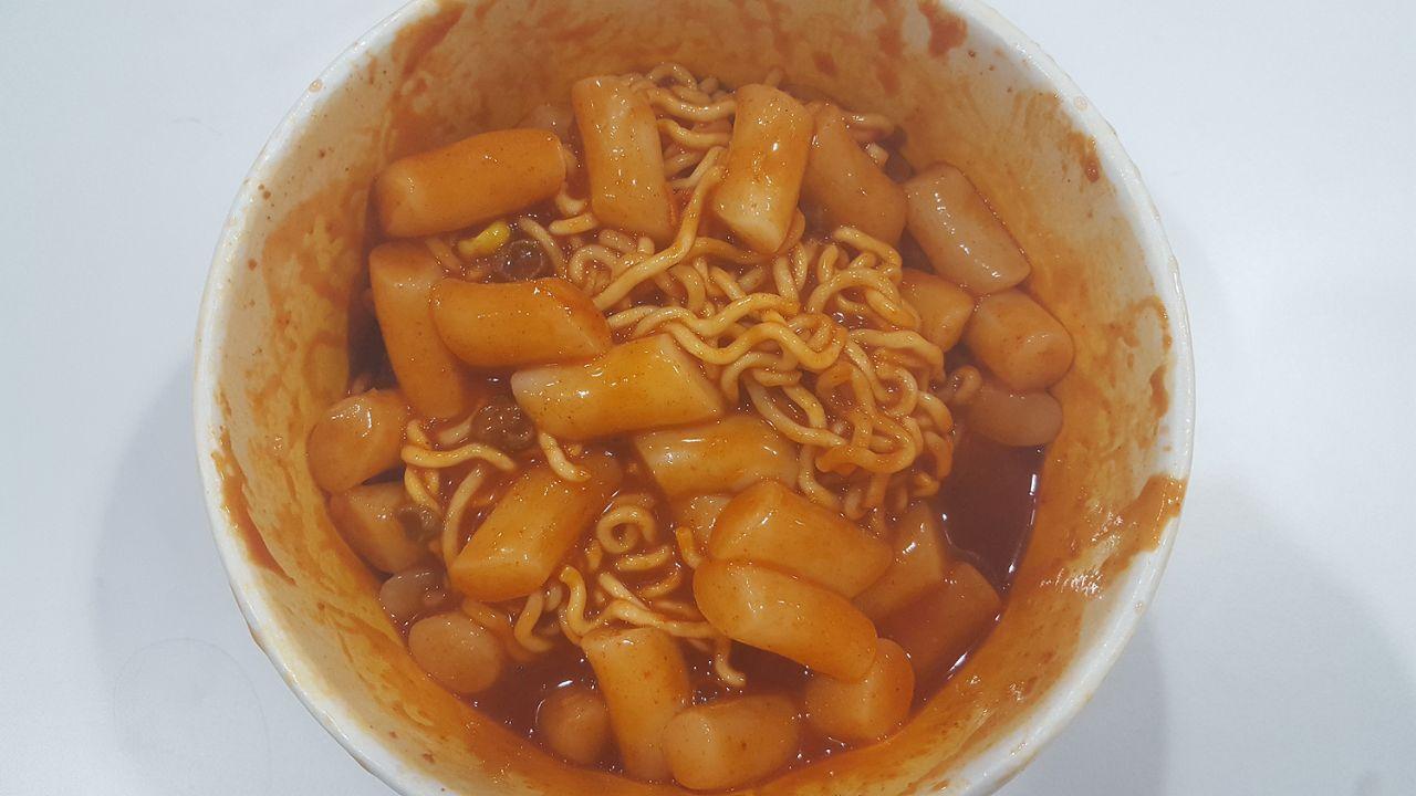 Spicy rice cakes mixed with noodles, illustrating a key step in creating a Mark meal, with chopsticks ready for mixing.