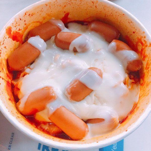 A bowl of Mark meal with sausages and melted cheese on top, showcasing a popular Korean convenience store snack enjoyed for its savory flavors.